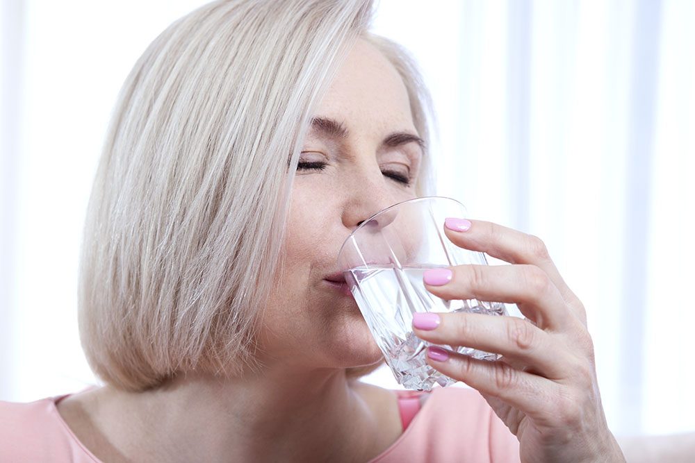 Portrait beautiful middle aged woman drinking water in the morning